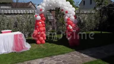 婚礼拱门由红白气球制成，婚礼仪式，绿色草坪。